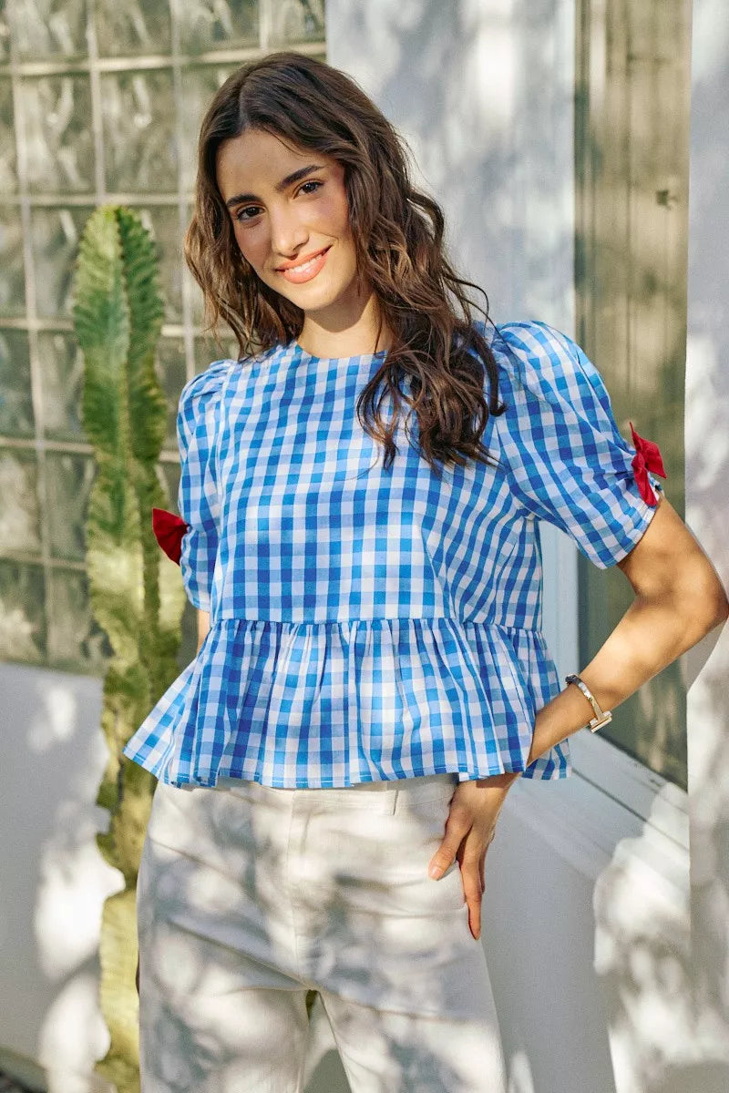 Blue gingham peplum blouse with short puff sleeves and red bow ties on both shoulders