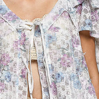 Close-up floral tie-front ruffle blouse with lace neckline and tassel trim, off-white