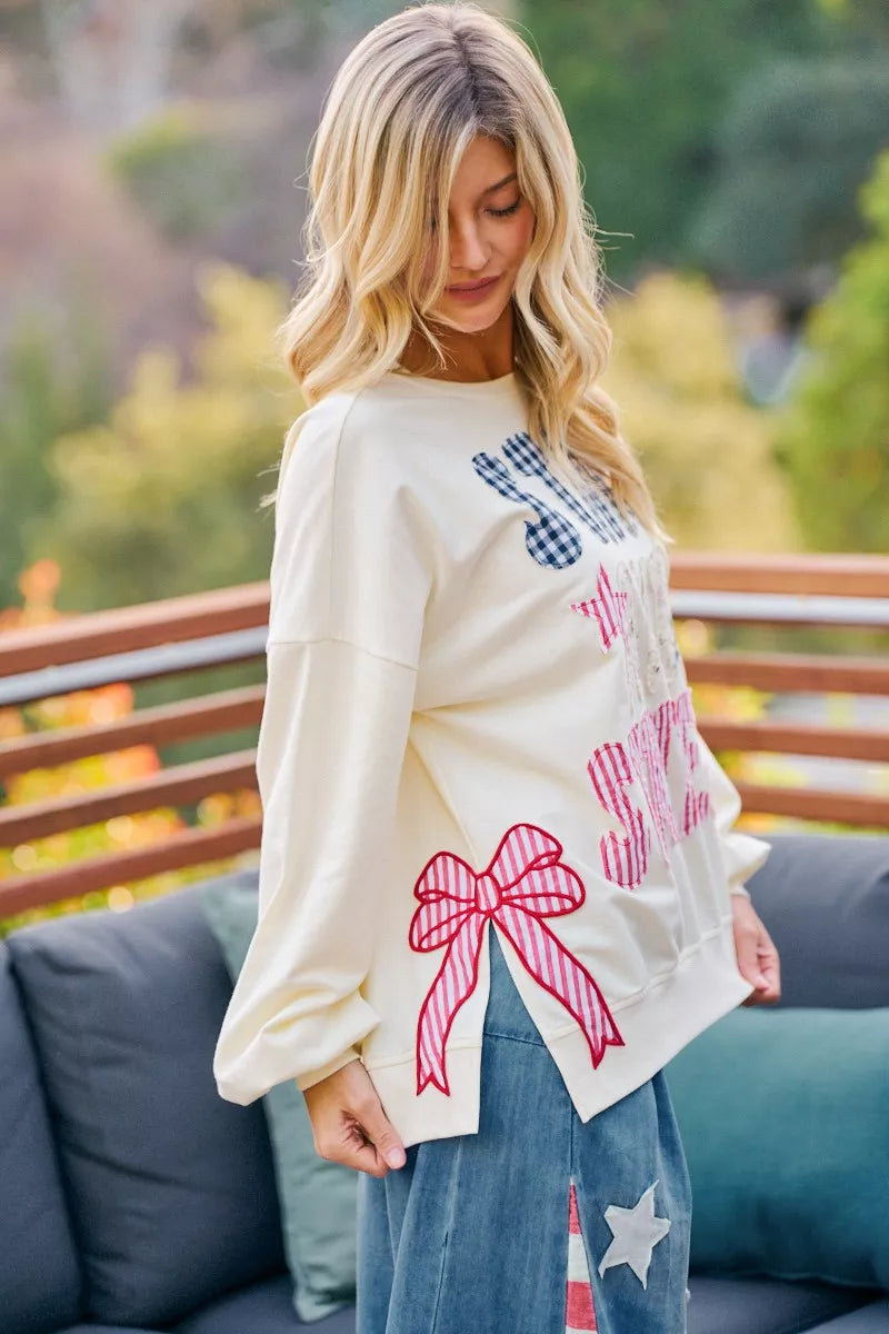 Cream crewneck sweatshirt with stars-and-stripes patch-style graphic and bow detail