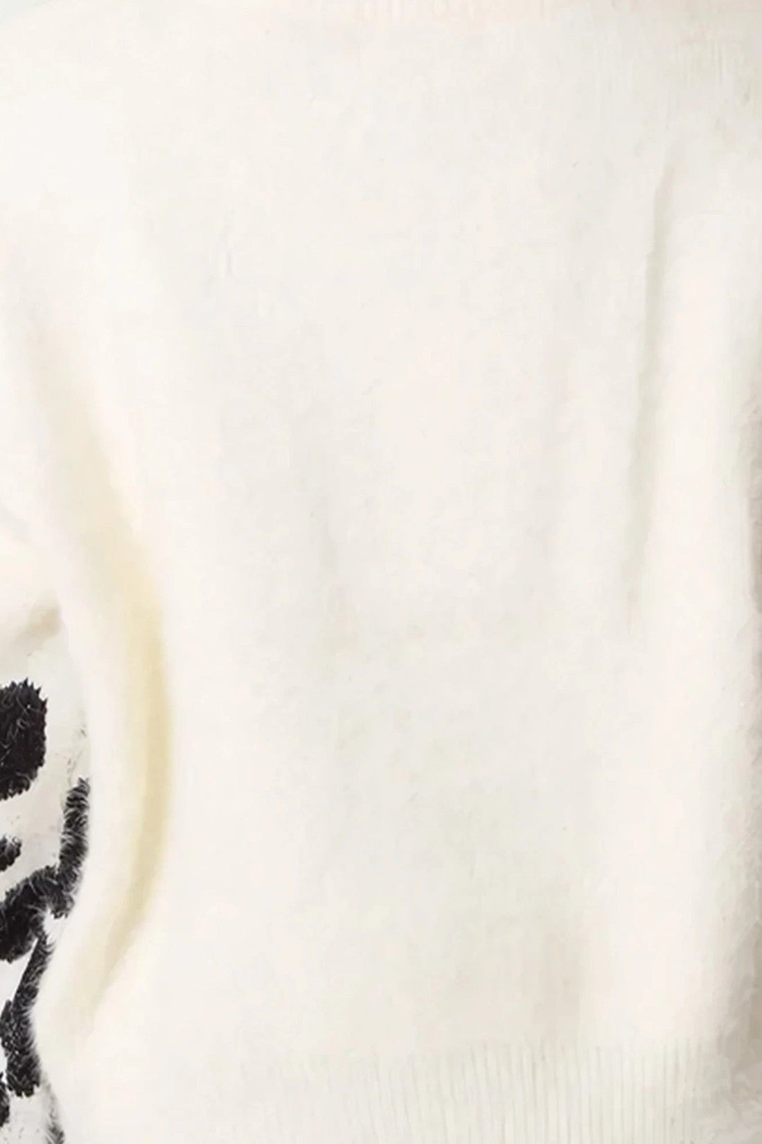 Ivory knit jumper fabric close-up with soft ribbed texture and black motif edge