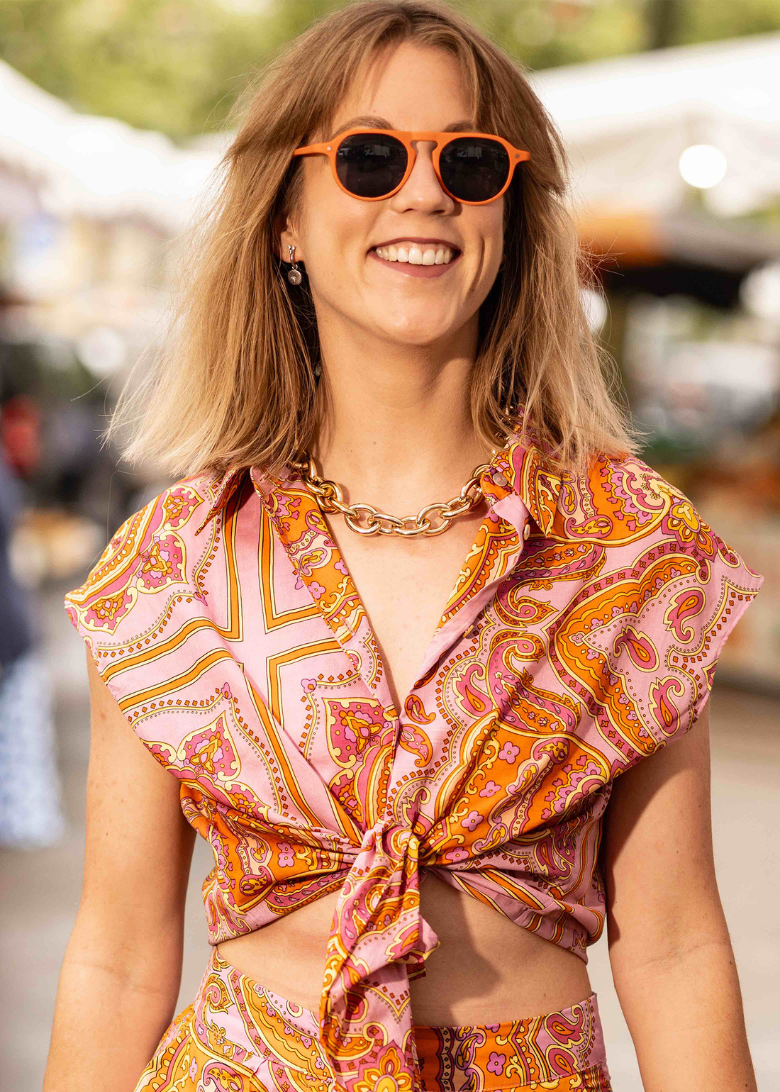 Sunglasses on a smiling woman with orange round frames and dark lenses