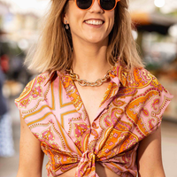 Pink rounded sunglasses with dark lenses on a smiling woman, close-up