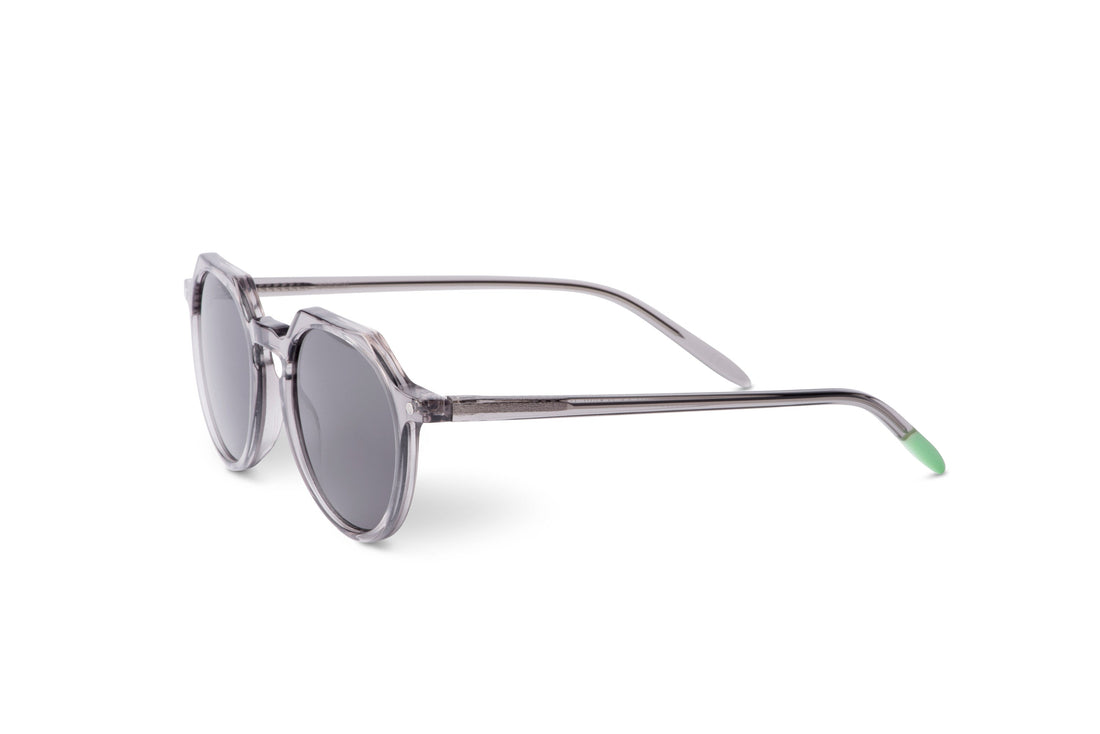 Round sunglasses with transparent gray frame and dark lenses, temple extended