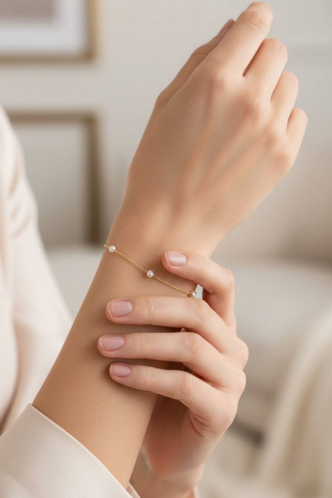 Pearl bracelet with spaced round white beads on the wrist, gold chain and clasp