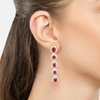 Gold-tone ruby gemstone drop earrings, five ruby-colored stones on ear