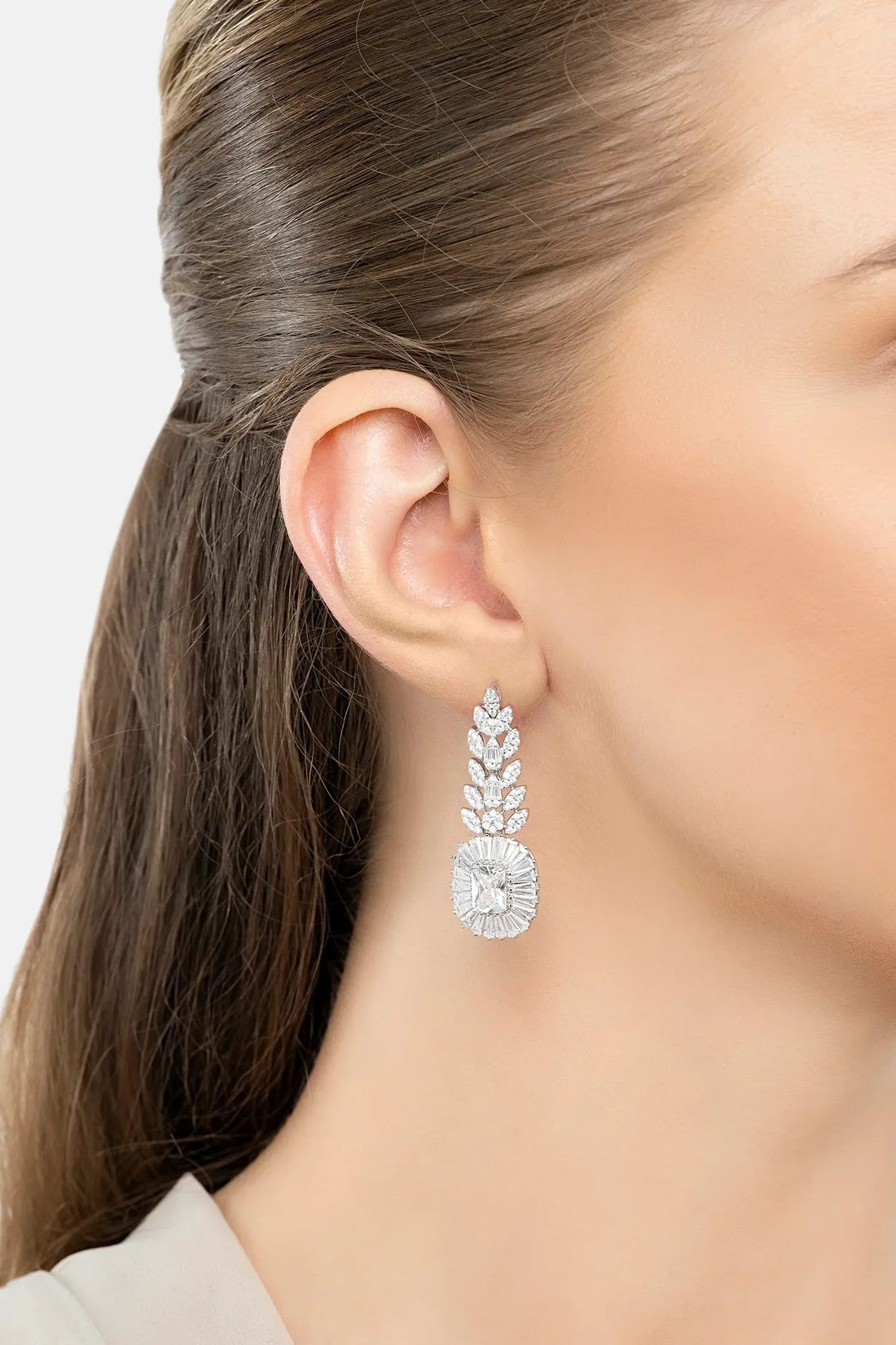 Silver-tone drop earrings with marquise clusters and round charm, close-up on ear