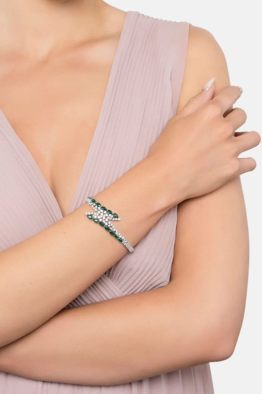 Silver tennis bracelet with emerald green stones on a model’s wrist