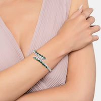 Silver tennis bracelet with emerald green stones on a model’s wrist