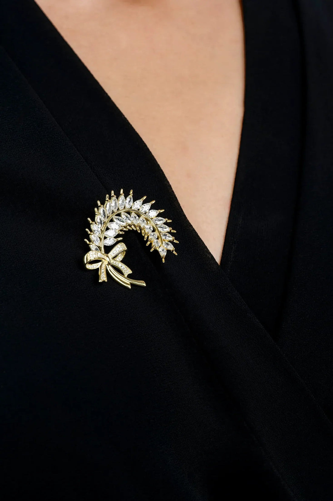 Gold laurel leaf ribbon brooch with crystal-like stones on black fabric