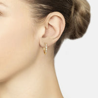 Gold hoop earrings with baguette-cut clear stones, worn on ear