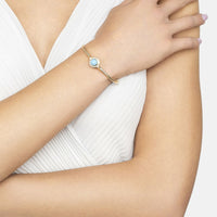 Gold bangle bracelet with turquoise oval center on wrist