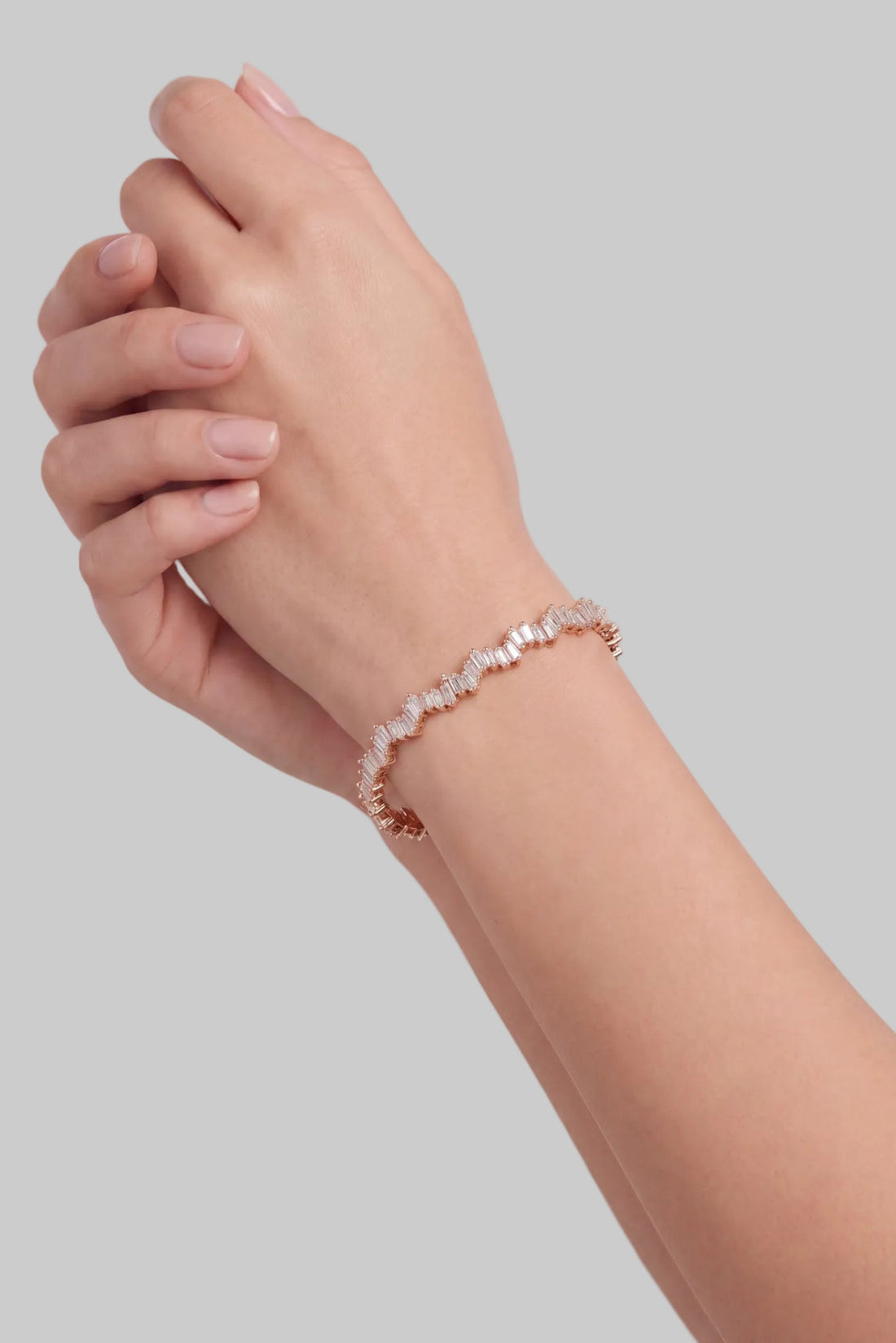 Rose gold ice cuff bangle with baguette-cut clear stones on wrist