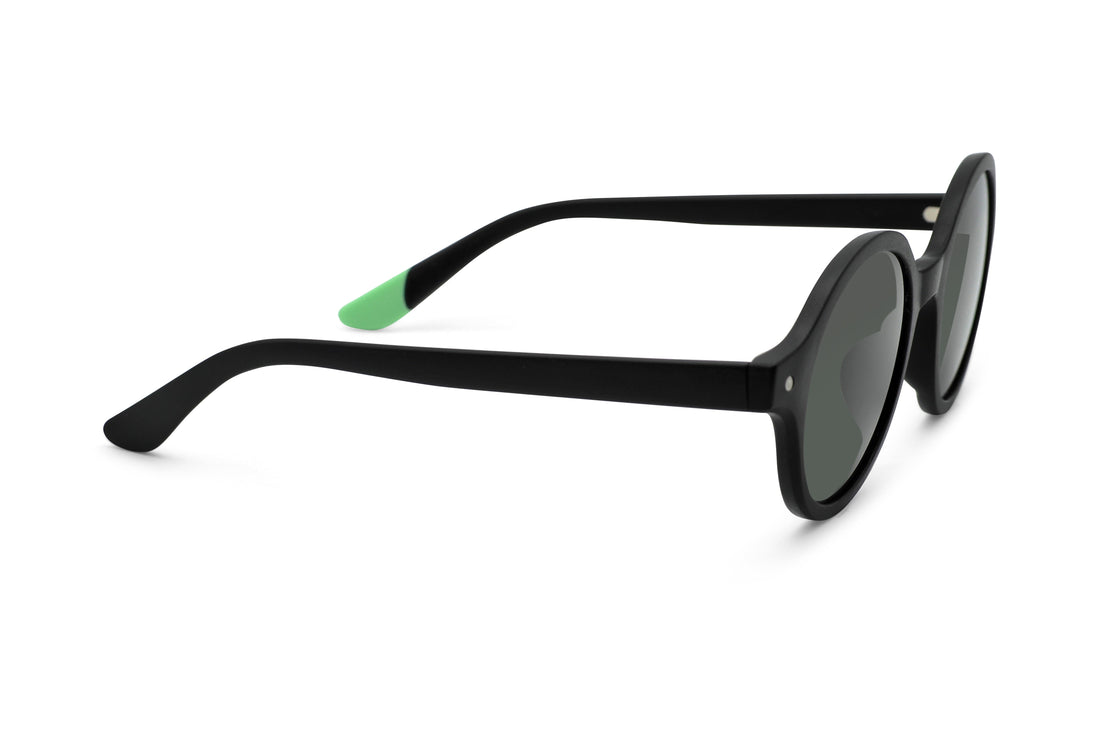 Black round sunglasses profile view with green temple tip and dark lenses