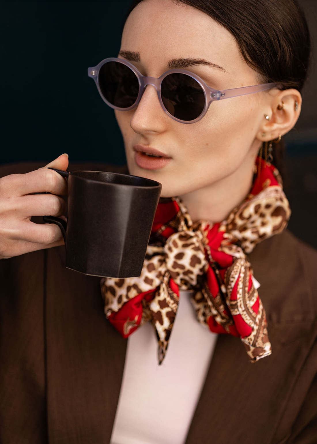 Woman wearing black round sunglasses with dark lenses and green temple accents