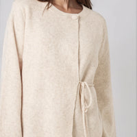 Beige knit cardigan with round neck and adjustable side ties; wide sleeves