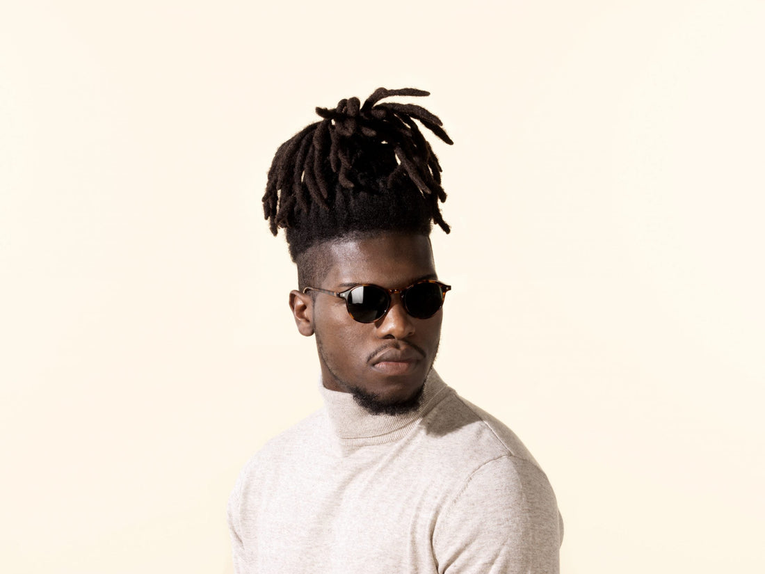 Tortoise sunglasses on person, dark lenses and rounded frames