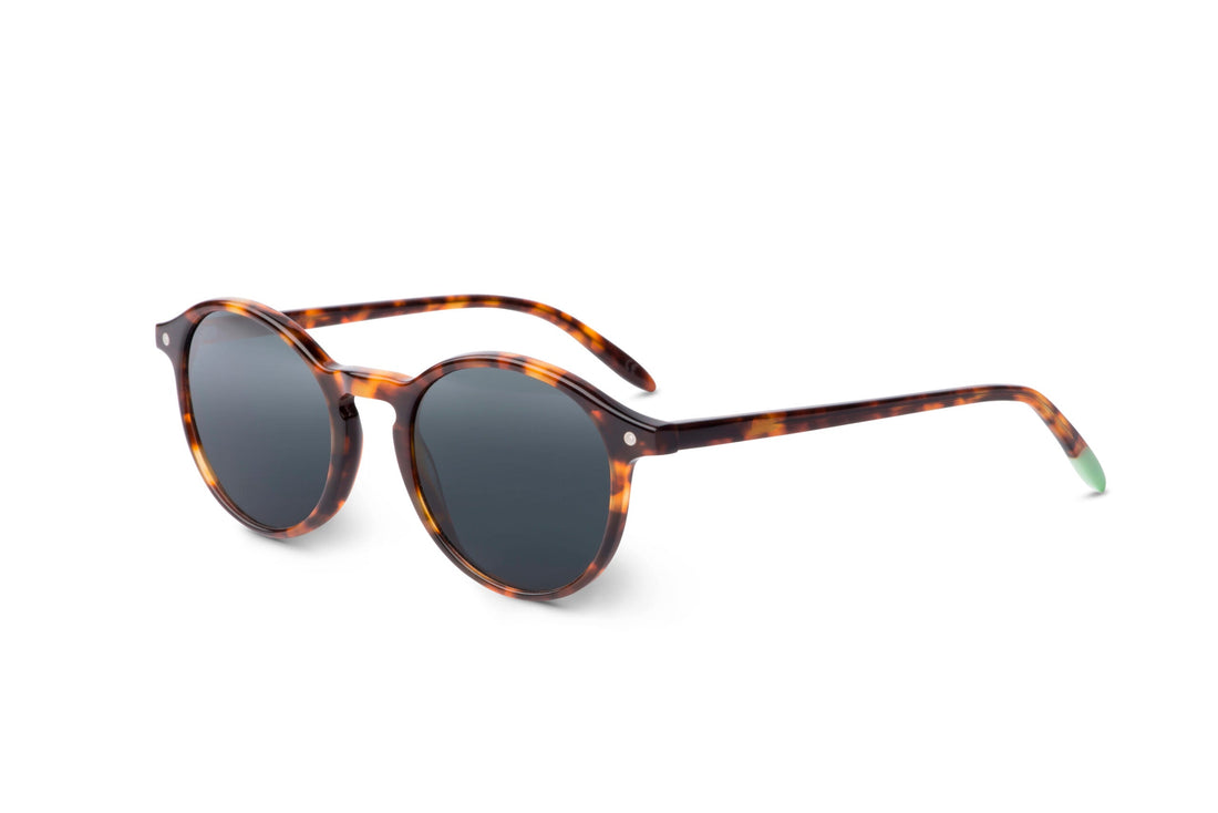 Tortoise sunglasses, side view, dark round lenses with thin green-tipped temple arms