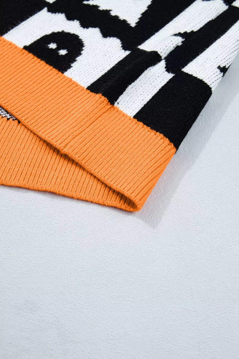 Black checkerboard ghost sweater with orange ribbed hem