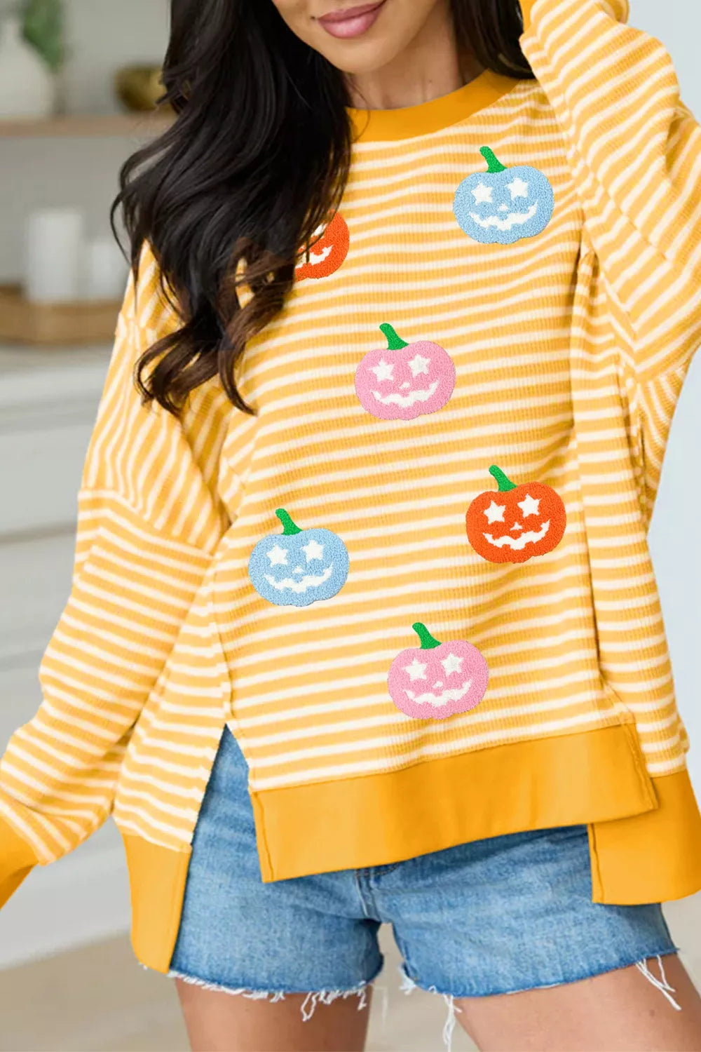 Yellow striped Halloween pullover with colorful pumpkin faces and drop-hem panel