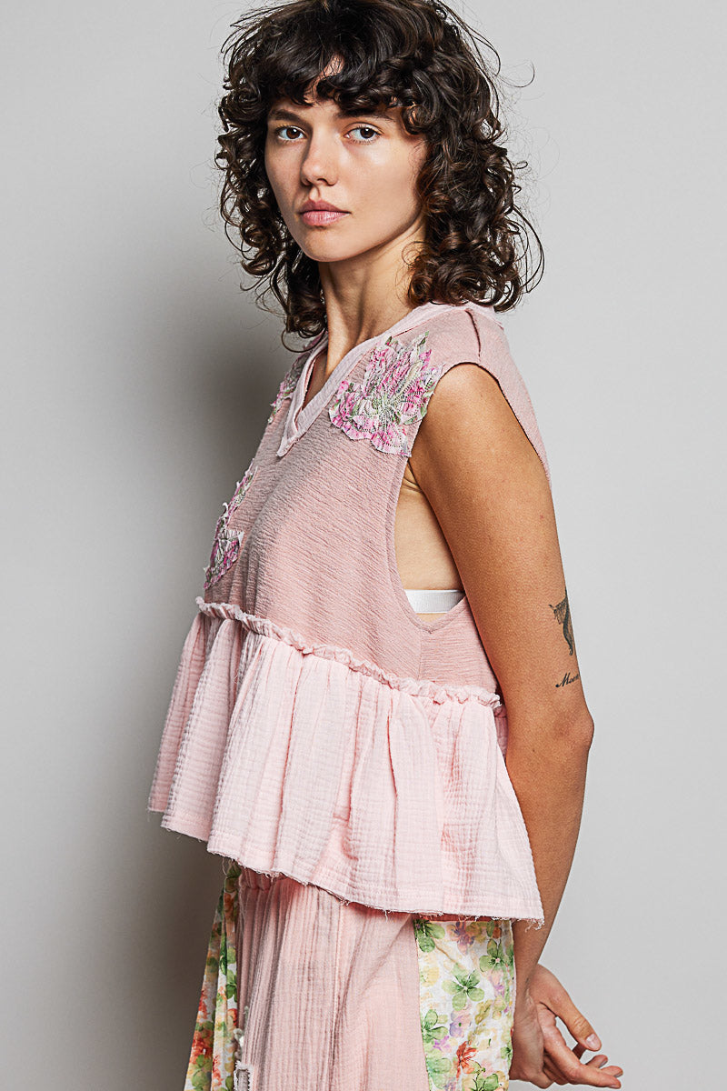 Powder pink sleeveless top with V-neck, floral shoulder patch and gathered peplum
