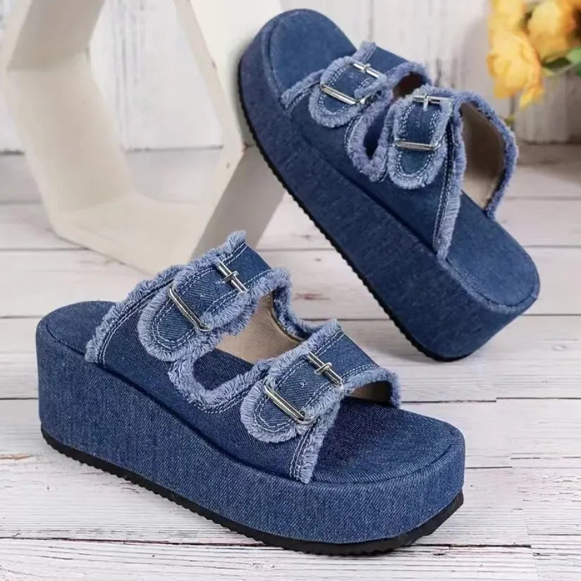 Blue denim platform wedge sandals with raw-edged straps and metal buckle closures