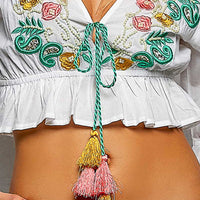 Ivory blouse neckline with colorful floral embroidery and tassel drawstring