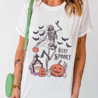 White Halloween graphic T-shirt front: skeleton with bats, pumpkins, and 'STAY SPOOKY'