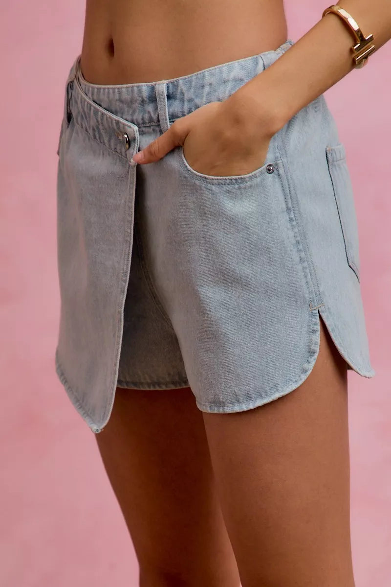Washed light blue denim wrap skort with button closure and curved front overlay