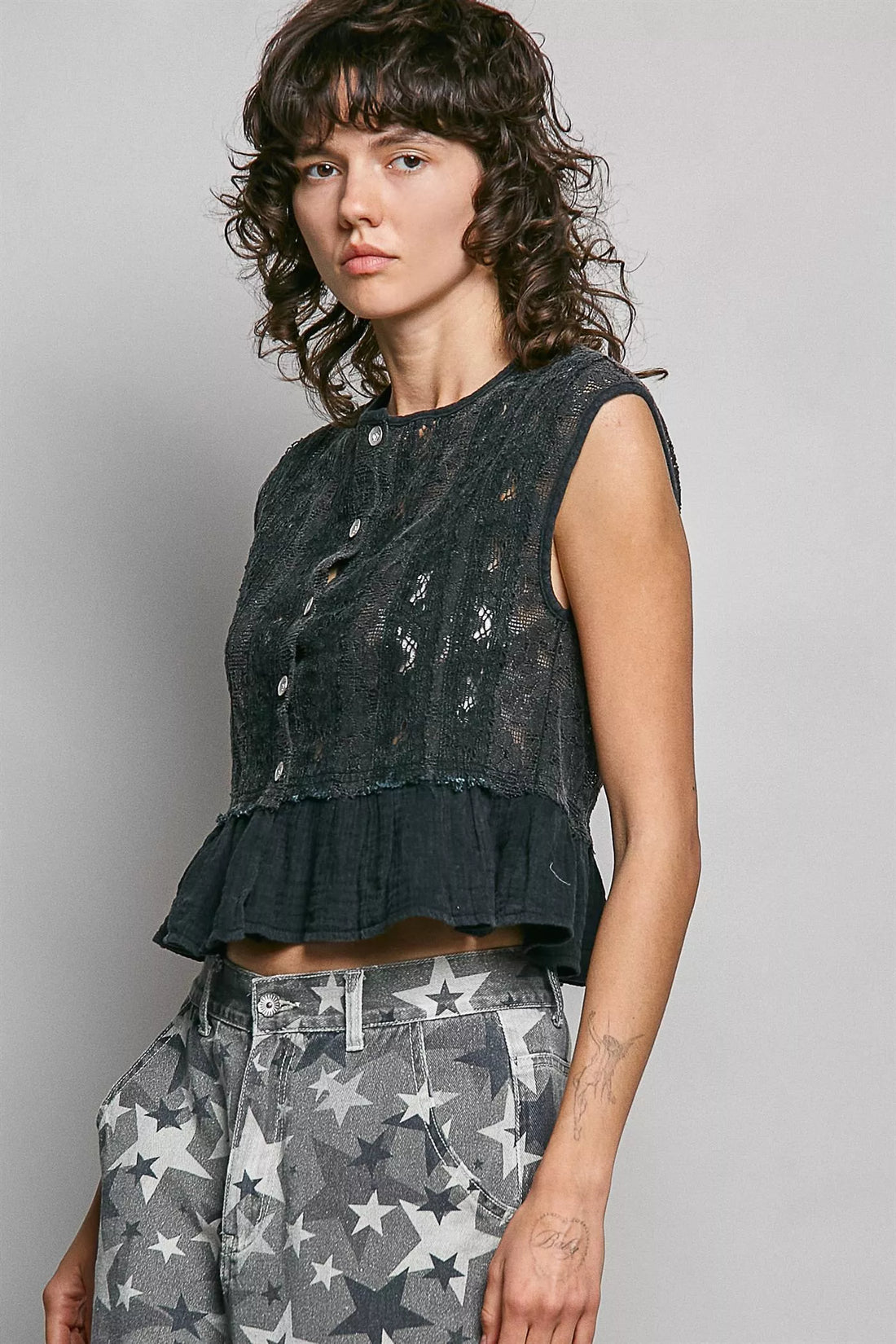 Black lace sleeveless peplum top with round neck, button placket, and ruffled hem