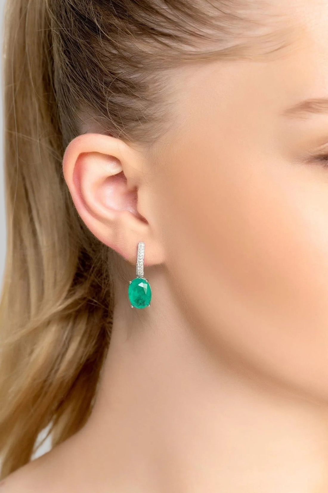 Silver drop earrings with emerald-green oval stone and pave top, close-up