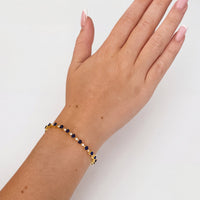 Gold-tone tennis bracelet with blue faceted stones on an open hand