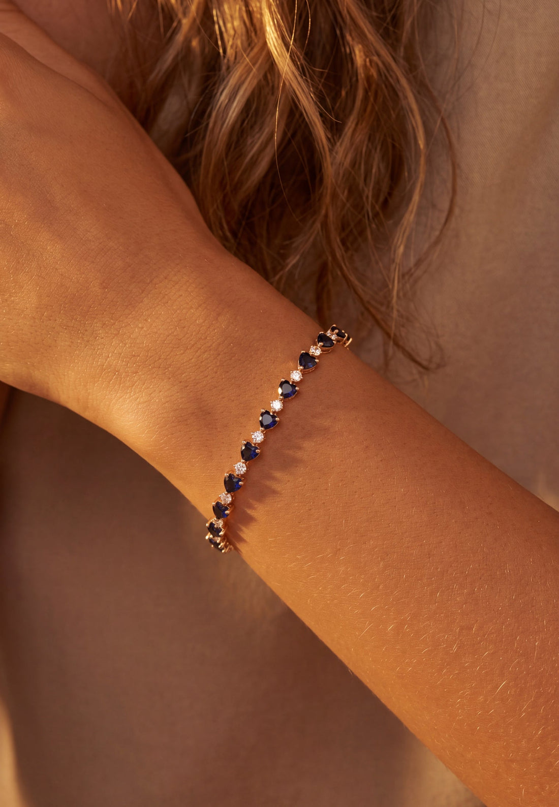 Gold-tone bracelet on wrist with blue faceted stones in repeating links