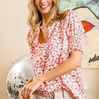 Orange floral V-neck top with smocked puff sleeves and lightly gathered neckline