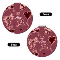 Round compact mirror with pink designs on a white background