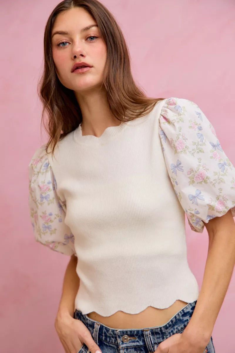 White ribbed sweater top with short floral puff sleeves and scalloped bottom edge