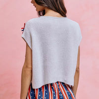 Off-white dolman sweater top from the back view, showing knit texture and bow trim