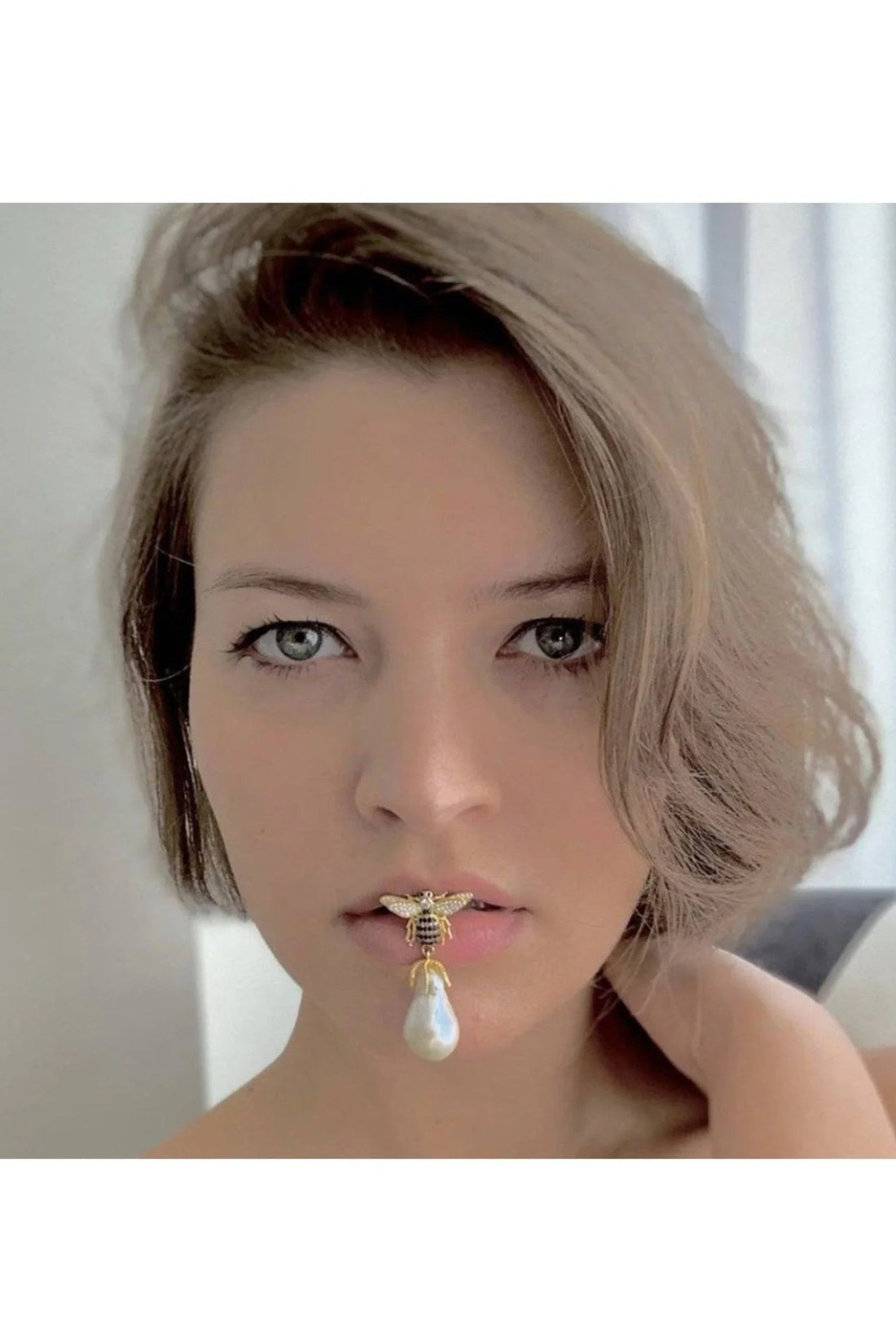 Bee-shaped pearl drop earrings in gold tone with crystal wings, worn