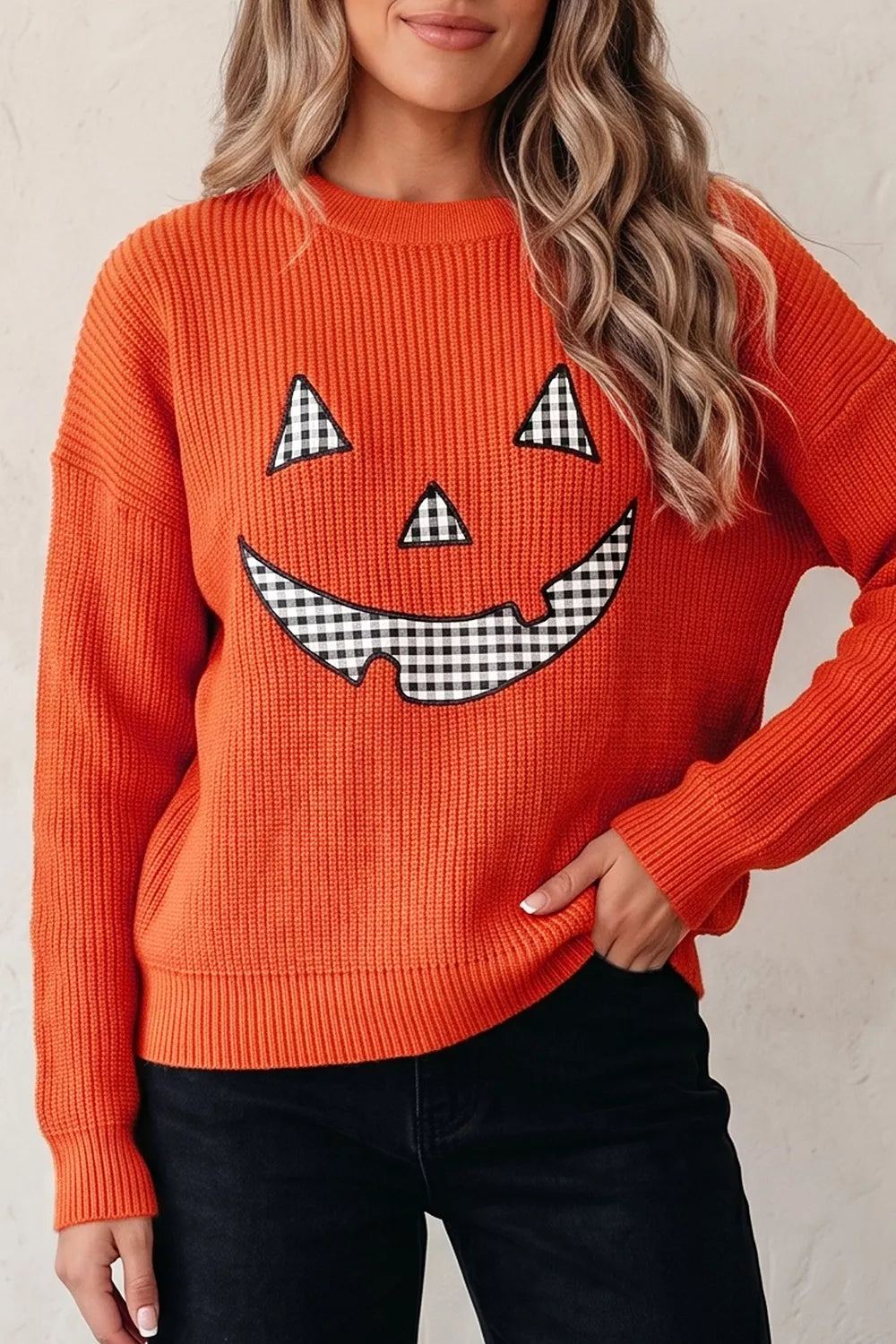 Orange knit sweater with jack-o-lantern face graphic and round crew neck