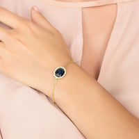 Gold oval blue gemstone bracelet shown on wrist