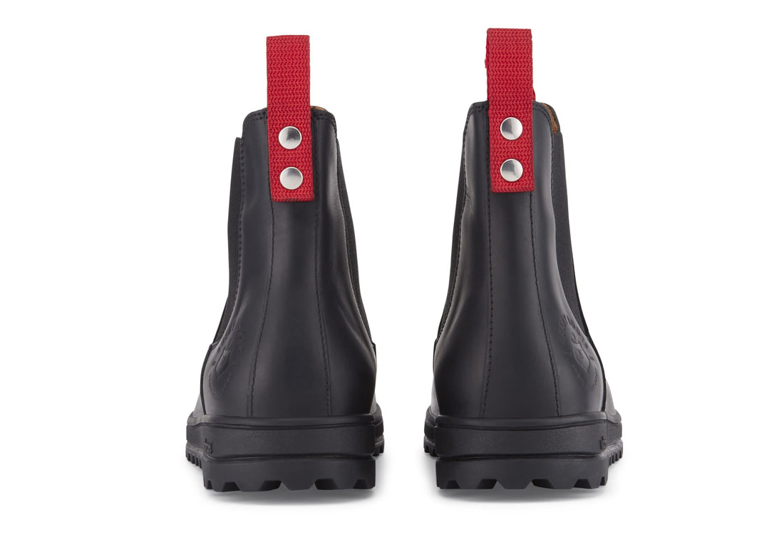 Rear view of black leather Chelsea boots with red pull tabs and lug soles.
