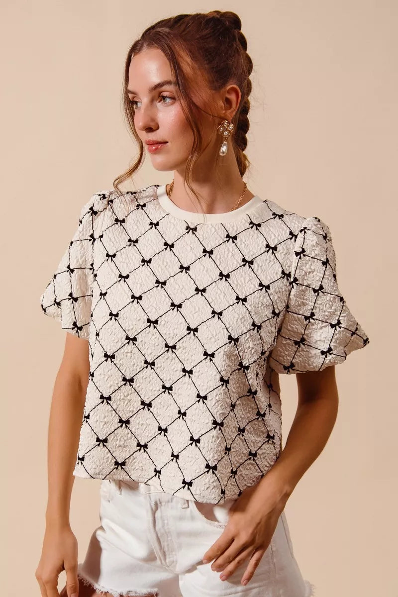 Ivory woven bubble sleeve top with black bow texture pattern, short puff sleeves