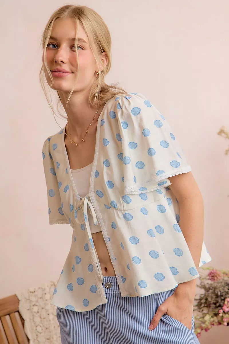 Ivory dot-print tie-front blouse with short flutter sleeves and V-neck detail.