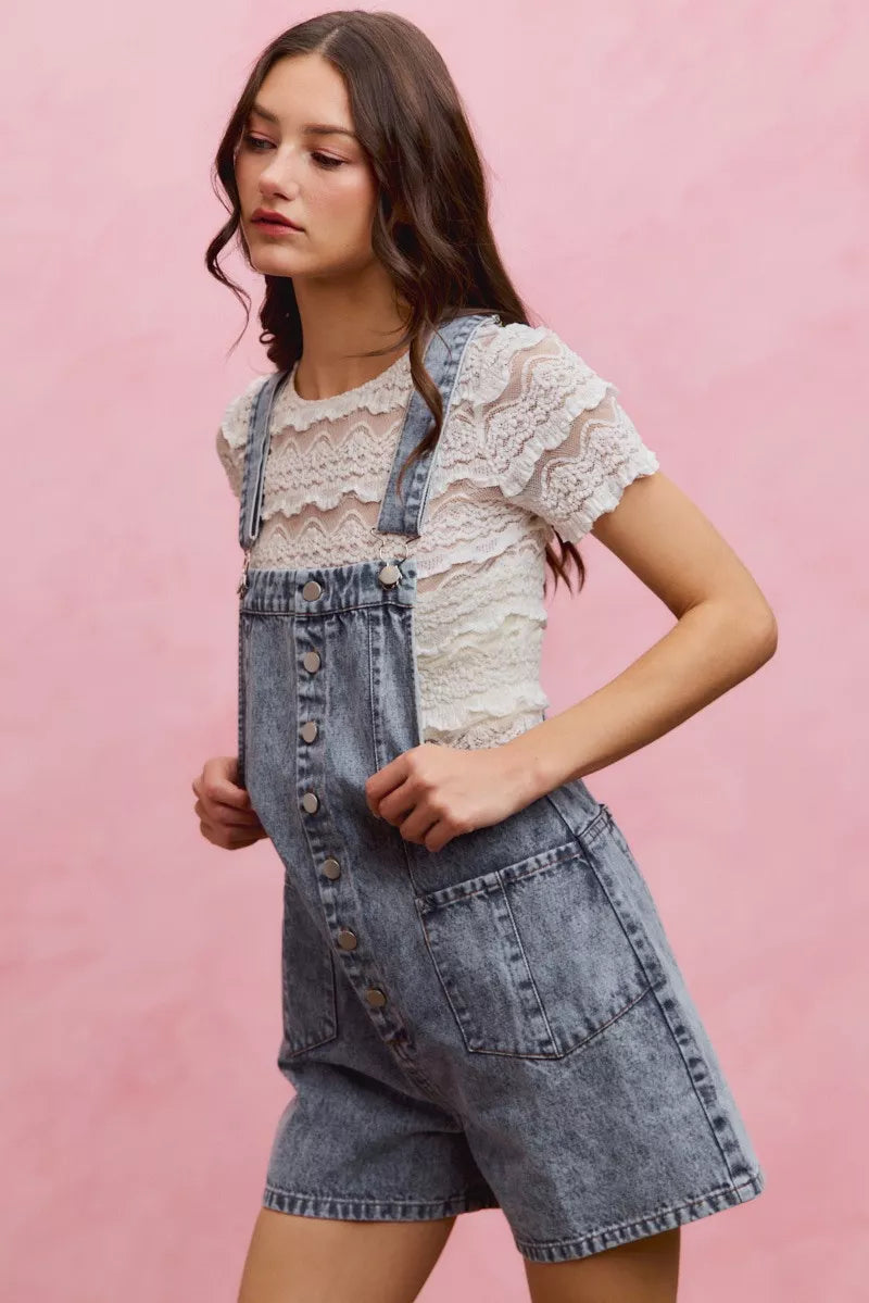 Light wash denim overall romper with adjustable straps, button front, and side patch pocket