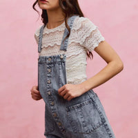 Light wash denim overall romper with adjustable straps, button front, and side patch pocket