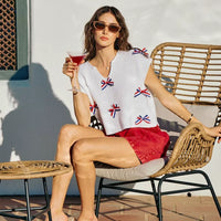 Off-white dolman sweater with scattered red-white-blue ribbon bow trim