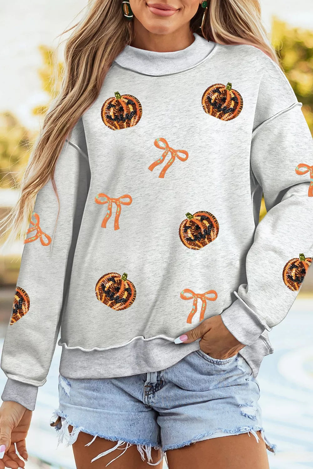 Light gray Halloween sweatshirt with orange sequin pumpkin faces and bow patterns