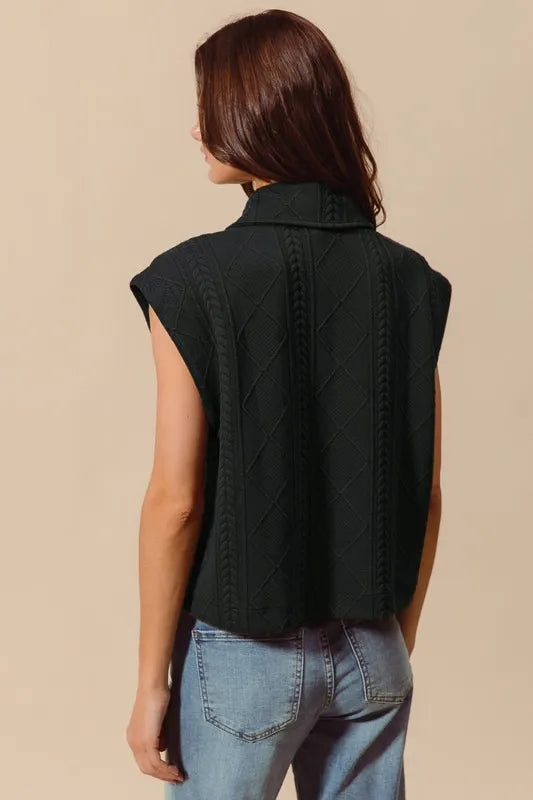 Black knit quilted vest with cable pattern, no visible front buttons