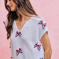 Off-white knit dolman sweater top with ribbon bow accents along the front and sleeve
