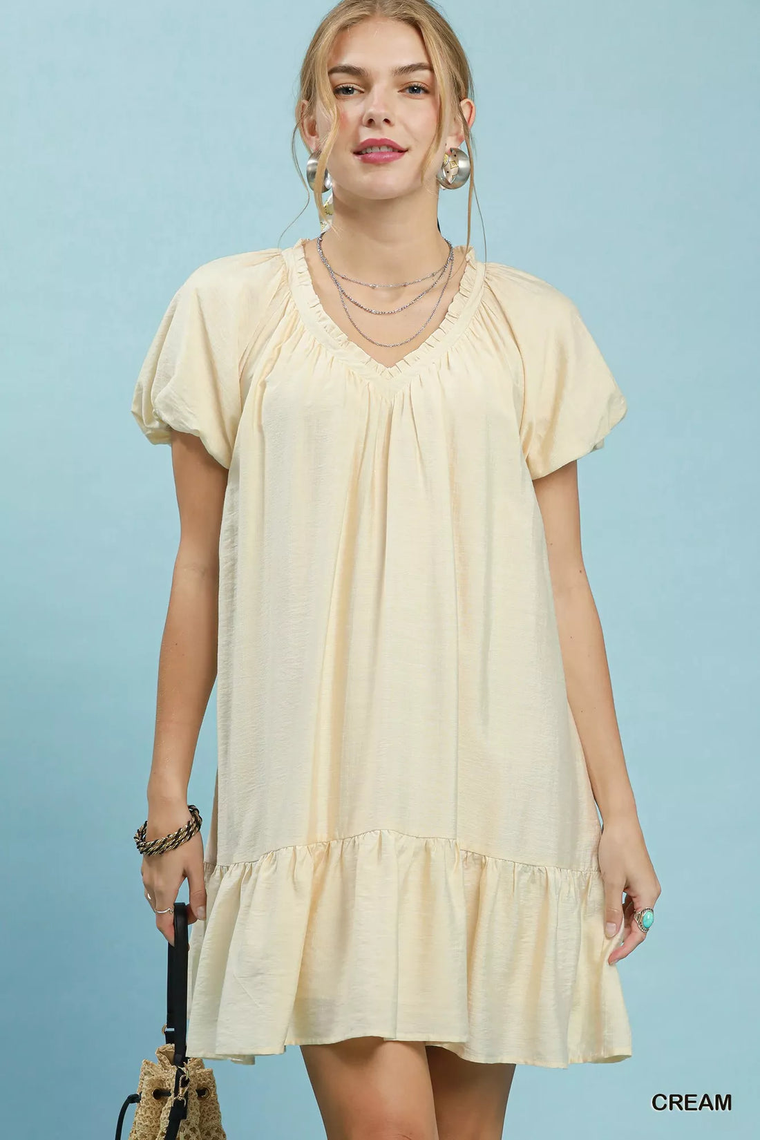 Cream mini shift dress with V-neck and ruffle hem, short puff sleeves.