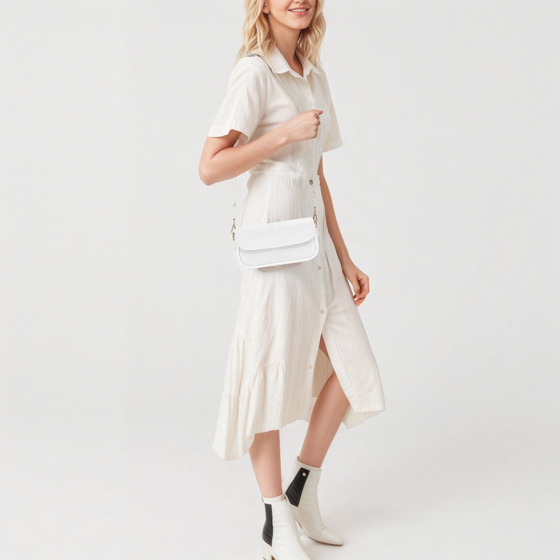 White mini shoulder bag with gold chain strap and flap, worn crossbody.